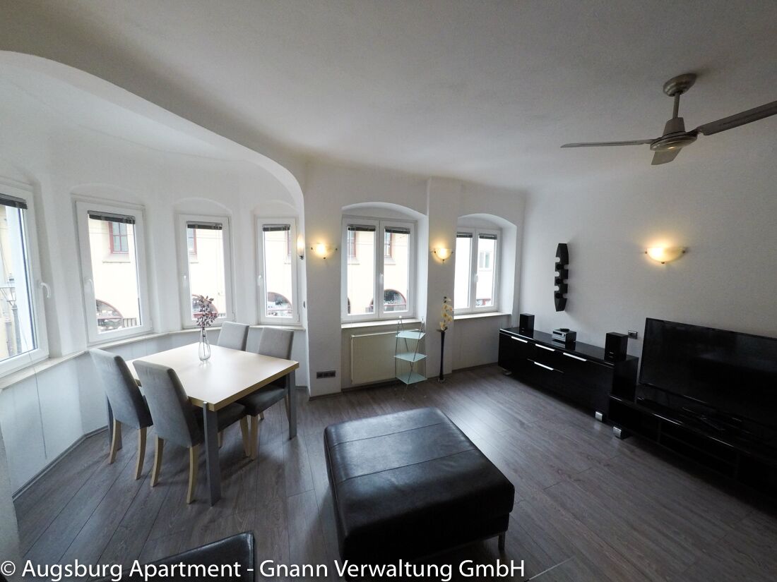 Wohnzimmer mit Essplatz und Erkerfenstern in einem möblierten Apartment in Augsburg